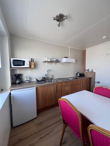 a kitchen with a white table and a white refrigerator at Stóra-Ásgeirsá Horse Farm Stay in Víðigerði