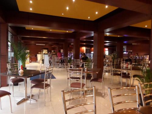 クルネーガラにあるBright Bravo Hotelのテーブルと椅子、背景の人々が並ぶレストラン