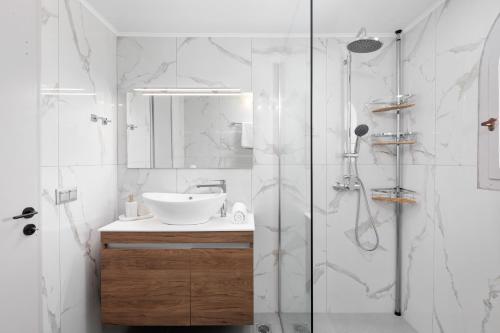 a white bathroom with a sink and a shower at Kalami Lookout Villa in Kalami