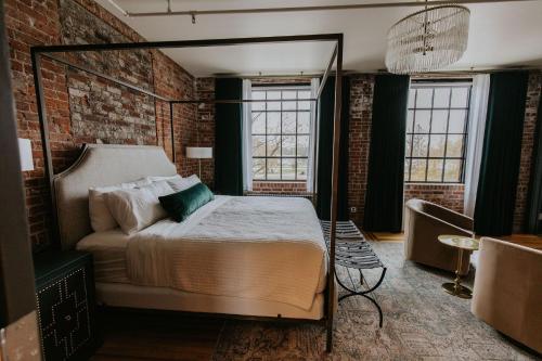 a bedroom with a canopy bed in a brick wall at HATCHERY HOTEL & EVENT CENTER in La Crosse