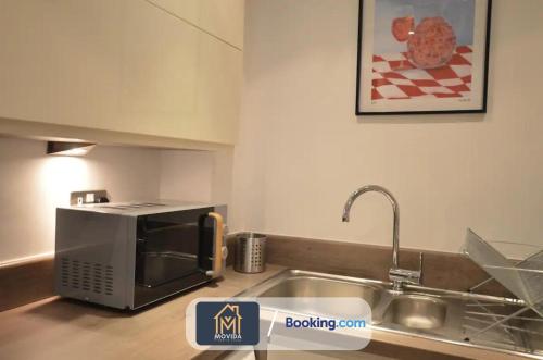 a kitchen with a sink and a microwave at Beautiful Apartment Next To LGI By Movida Property Group Short Lets & Serviced Accommodation in Leeds