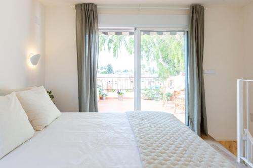 1 dormitorio con cama blanca y puerta corredera de cristal en La Casita del Malecón, en Murcia