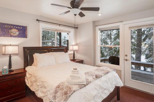 a bedroom with a bed with a ceiling fan and windows at Community Private Beach on Whitefish Lake and About a Mile to Downtown in Whitefish