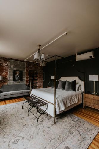 a bedroom with a canopy bed and a brick wall at HATCHERY HOTEL & EVENT CENTER in La Crosse