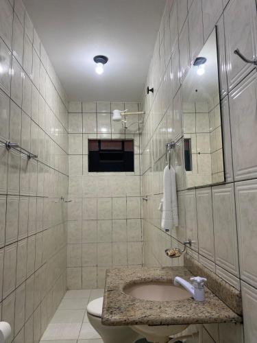 a bathroom with a sink and a toilet and a mirror at Pousada Aguas Quentes in Barra do Garças