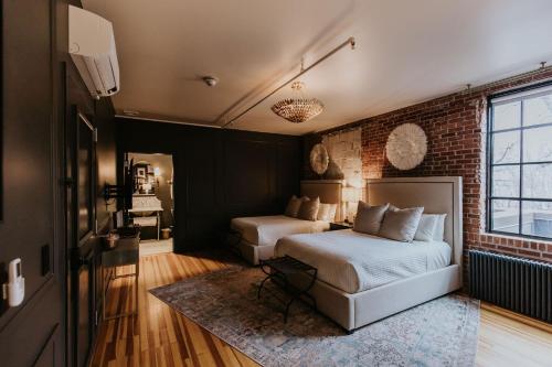 a bedroom with two beds and a brick wall at HATCHERY HOTEL & EVENT CENTER in La Crosse