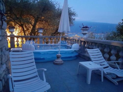 a patio with two chairs and a tub with an umbrella at Villa Pinetina in Gargnano