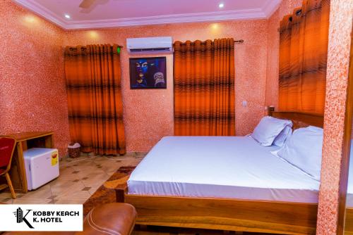 1 dormitorio con 1 cama grande y cortinas de color naranja en Kobby Keach K. Hotel, en Kumasi