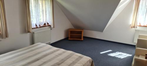 a attic room with a bed and a table and windows at Rezidence Lipka in Králíky