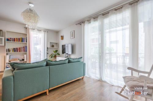 LʼÎle-Saint-Denis的住宿－Very pleasant and bright apartment，客厅设有绿色沙发和大窗户