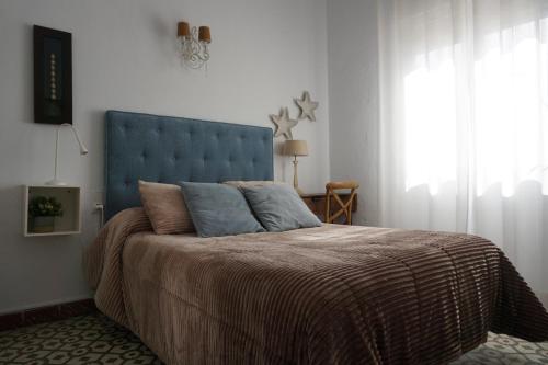 a bed with a blue headboard in a bedroom at Montserrat Casa del Mar in Chipiona