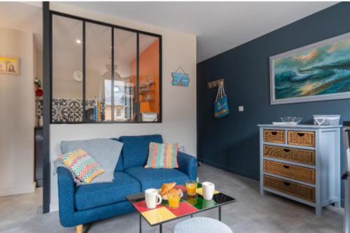 un salon avec un canapé bleu et une table dans l'établissement Norman studio in city center, à Honfleur