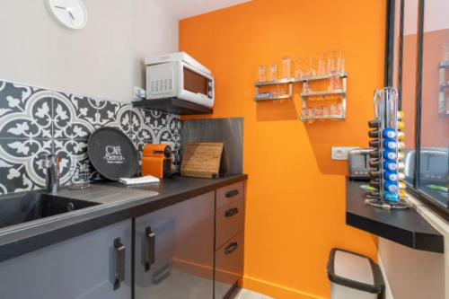 - une cuisine avec un mur orange et un évier dans l'établissement Norman studio in city center, à Honfleur