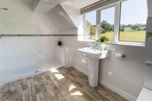 Un baño blanco con lavabo y bañera. en The Breckland at Sugar Lane Farm, en Bollington