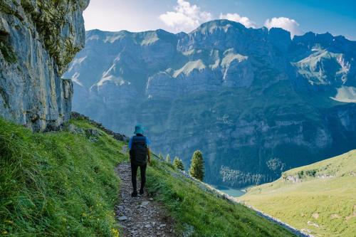 a man walking down a path in the mountains at Workation Apartments - 24-7 Self-Checkin - Hotel Postigliun Sedrun in Sedrun