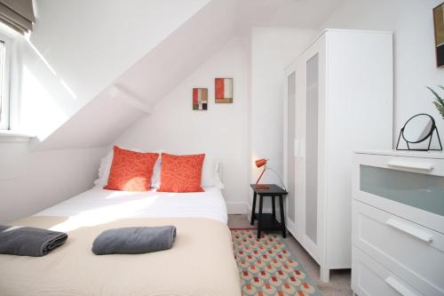 a white bedroom with a bed with orange pillows at Cozy 1 Bedroom Apartment | WIFI in Cardiff