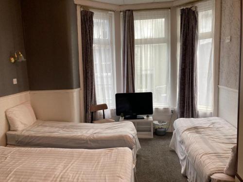 ブラックプールにあるIona Hotelのベッド2台とテレビが備わるホテルルームです。