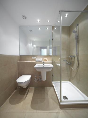 La salle de bains est pourvue de toilettes, d'un lavabo et d'une douche. dans l'établissement Meer & Strand - Haus Meeresstrand Ferienwohnung 202, à Scharbeutz