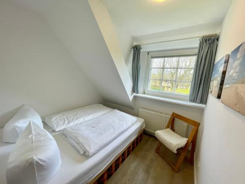 ein kleines Schlafzimmer mit einem Bett und einem Fenster in der Unterkunft Altes Friesenhaus Scheune in Morsum