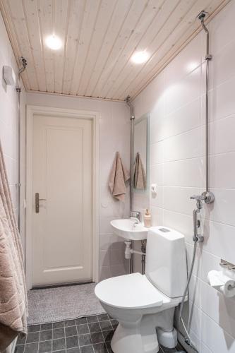 a white bathroom with a toilet and a sink at City Apartment Snowberry in Rovaniemi
