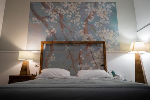 a bed with two pillows and a painting on the wall at Relais Villa Al Vento in Incisa in Valdarno