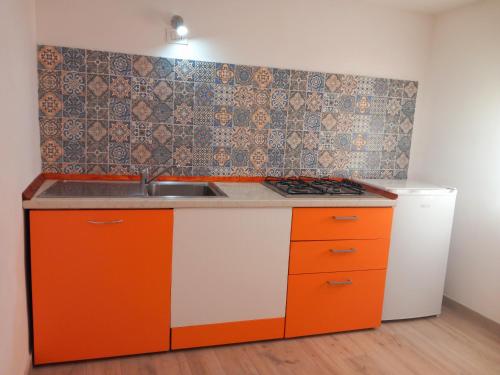 an orange and white kitchen with a sink and a refrigerator at RoofTop Home Stagnone in Marsala