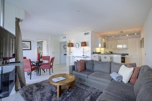 Il comprend un salon avec un canapé gris et une cuisine. dans l'établissement Carlton Riviera Cannes - Dernier étage - Palme d'Or, à Cannes