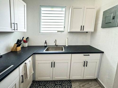 una cocina con armarios blancos y fregadero en Entire Vacation Home in San Juan - Fits 13, en San Juan