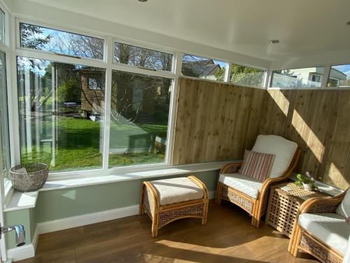 eine abgeschirmte Veranda mit Stühlen und Fenstern in der Unterkunft Meadow cottage in Haverfordwest