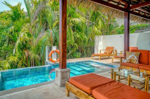 a resort pool with orange furniture and palm trees at Canto Del Mar #13 in Dominical