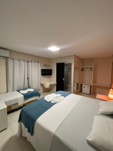 a large bedroom with two beds and a television at Aldeia das Flores Hotel in Goiânia