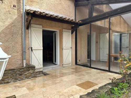 an outdoor patio with glass doors and a table at Maison au Pied de la Sainte Victoire in Puyloubier