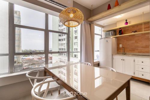 a kitchen with a table and chairs and a large window at Aptos modernos no centro de Floripa - VLR in Florianópolis