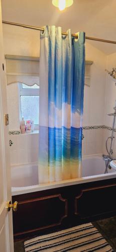 a bathroom with a bath tub with a shower curtain at Diamond in Abbey Wood