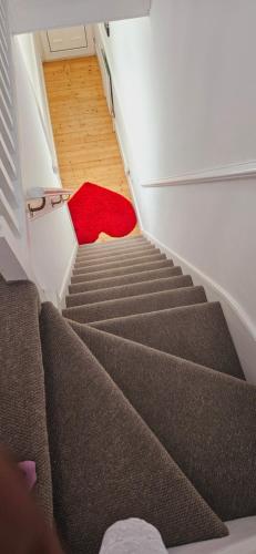 uma escada com um tapete vermelho num quarto em Diamond em Abbey Wood