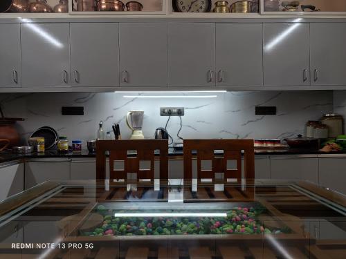 una mesa de cristal con 2 sillas en la cocina en Sree Nivas Homestay en Thiruvananthapuram