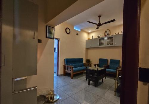 sala de estar con sillas azules y ventilador de techo en Sree Nivas Homestay, en Trivandrum