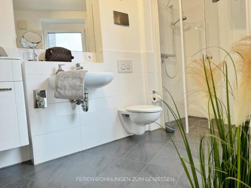 ein weißes Bad mit einem WC und einem Waschbecken in der Unterkunft De Kattuul - a88661 in Dorum Neufeld