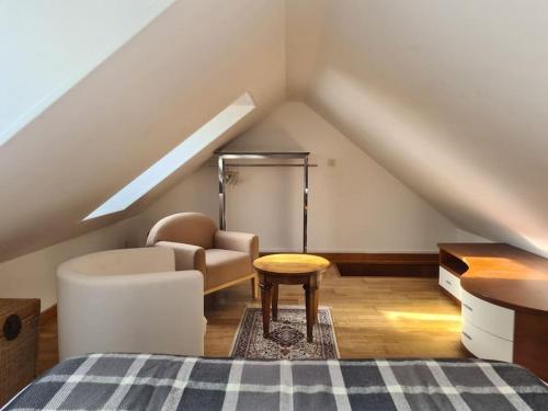 Cette chambre mansardée comprend un lit, une chaise et une table. dans l'établissement Maison de charme au Vallon du Stang-Alar, à Brest