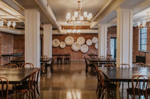 a dining room with tables and chairs and a brick wall at HATCHERY HOTEL & EVENT CENTER in La Crosse