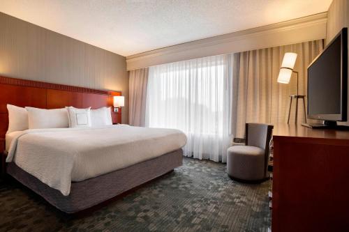 a hotel room with a bed and a flat screen tv at Courtyard by Marriott Champaign in Champaign