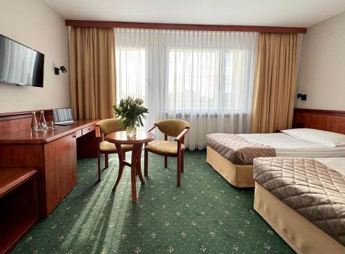 Habitación de hotel con cama, escritorio y mesa. en Senator, en Katowice