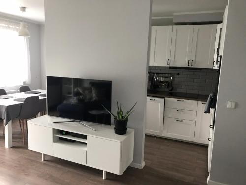 Il comprend une cuisine dotée d'une armoire blanche et d'une télévision. dans l'établissement Apartament na Szczecińskiej, à Gdańsk