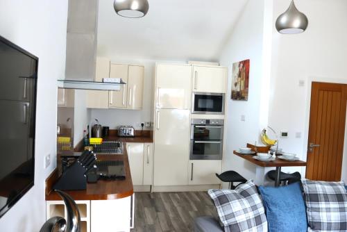 a small kitchen with white cabinets and a table at Ferndown Holiday Let in Ferndown