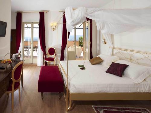 アッシジにあるジオット ホテル & スパのベッドルーム(天蓋付き白いベッド1台付)