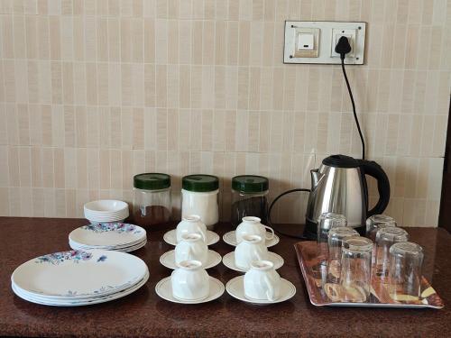 a counter with plates and cups and a coffee pot at Sunshine Villa & Homestay in Tiruchchirāppalli