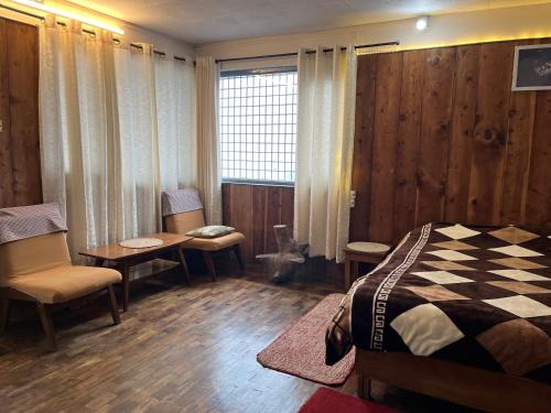 a bedroom with a bed and a table and chairs at Maayaa Ridge House in Kanatal