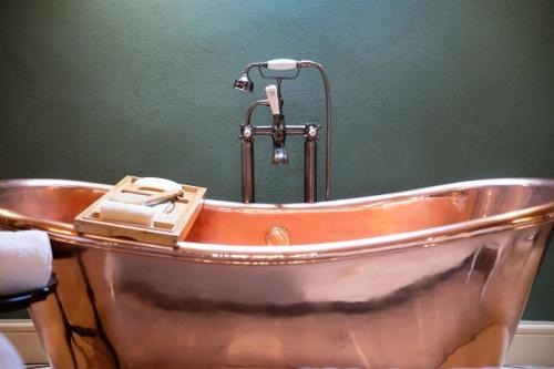 a copper bath tub with a water faucet in a bathroom at The Footmans Cottage in Longwitton