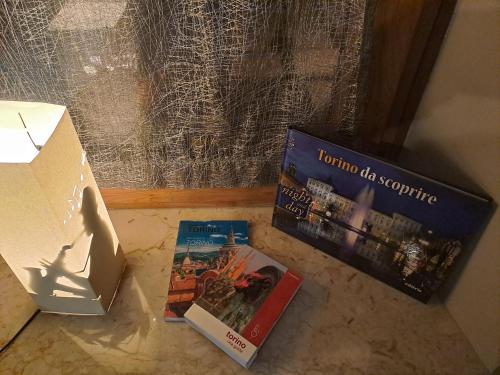 three books sitting on the floor next to a box at B&B Casa V-Ale in Collegno