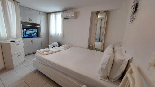a white bedroom with a bed and a television at Belva Blue Naxos Stylish, Naxos Town, near Beach in Naxos Chora